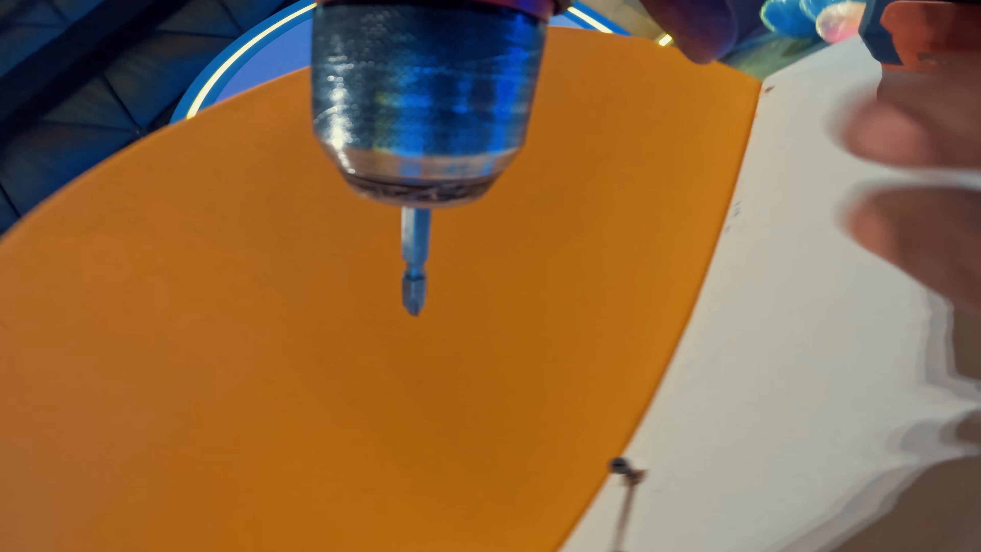 Close-up of a drill fixing an orange set panel