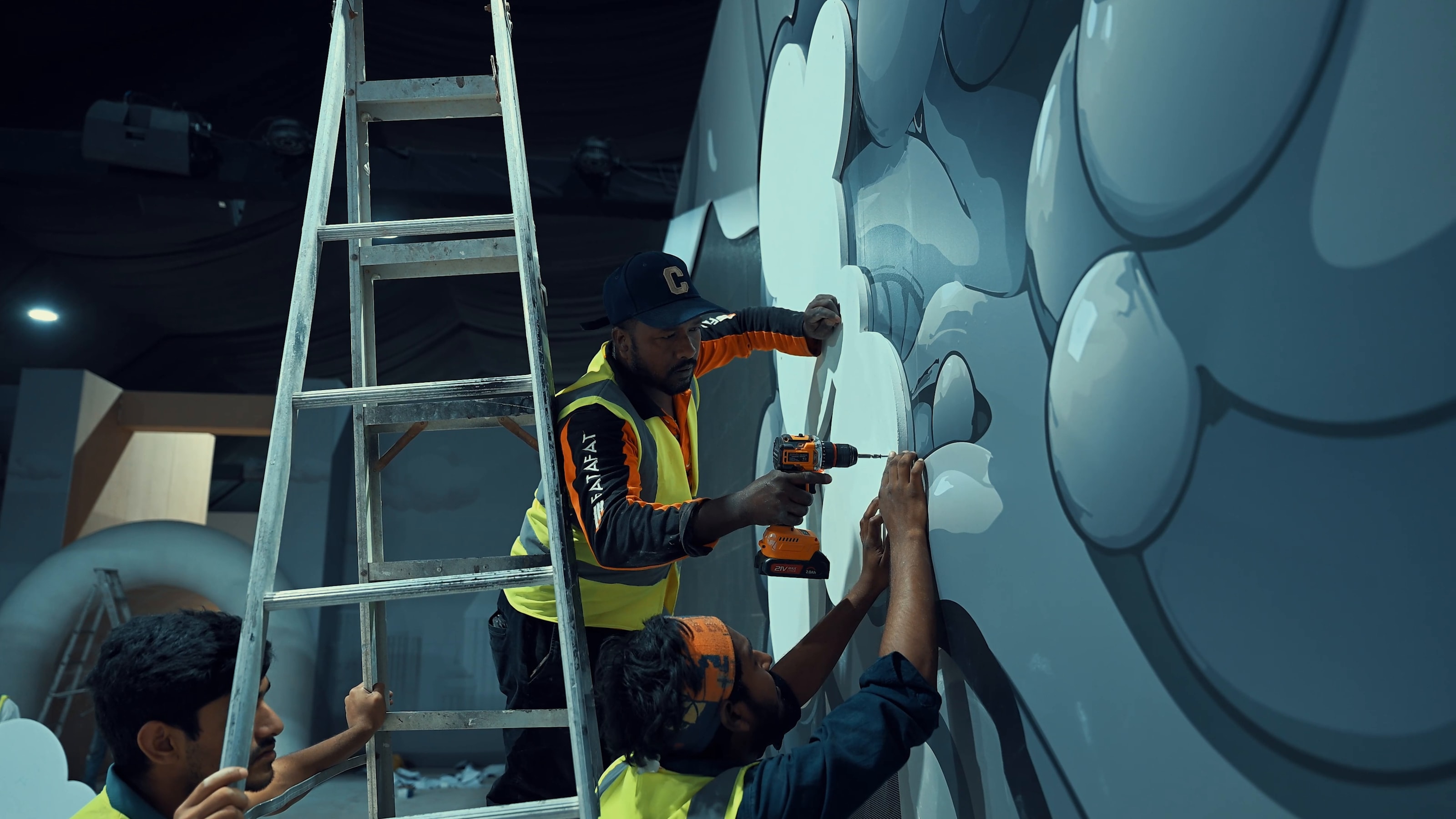Crew on a ladder fitting a sculpted cloud wall