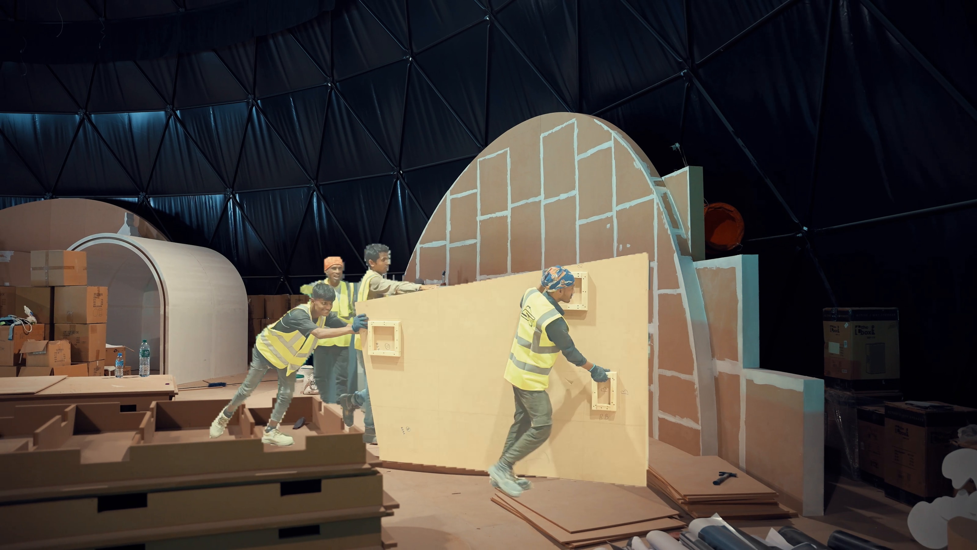 Crew carrying wall panels across the workshop floor