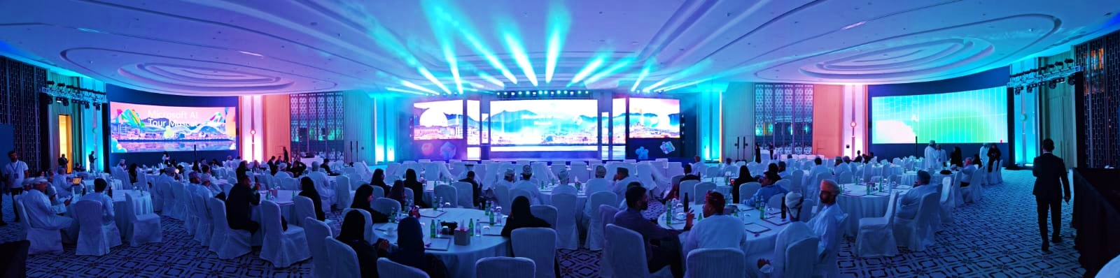 Panorama of the AI Tour ballroom with blue stage lighting