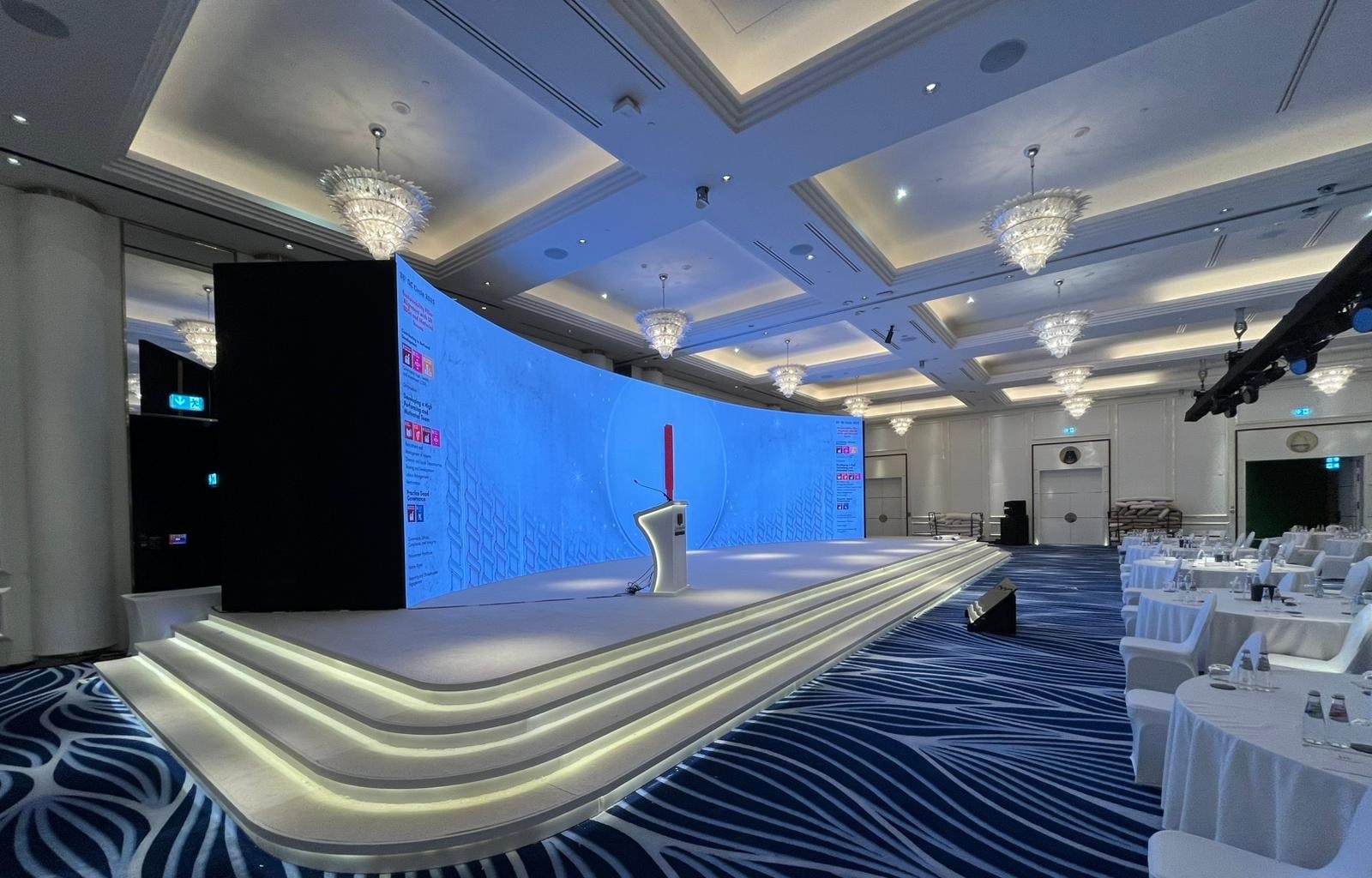 Curved LED wall and lit tiered stage in a ballroom