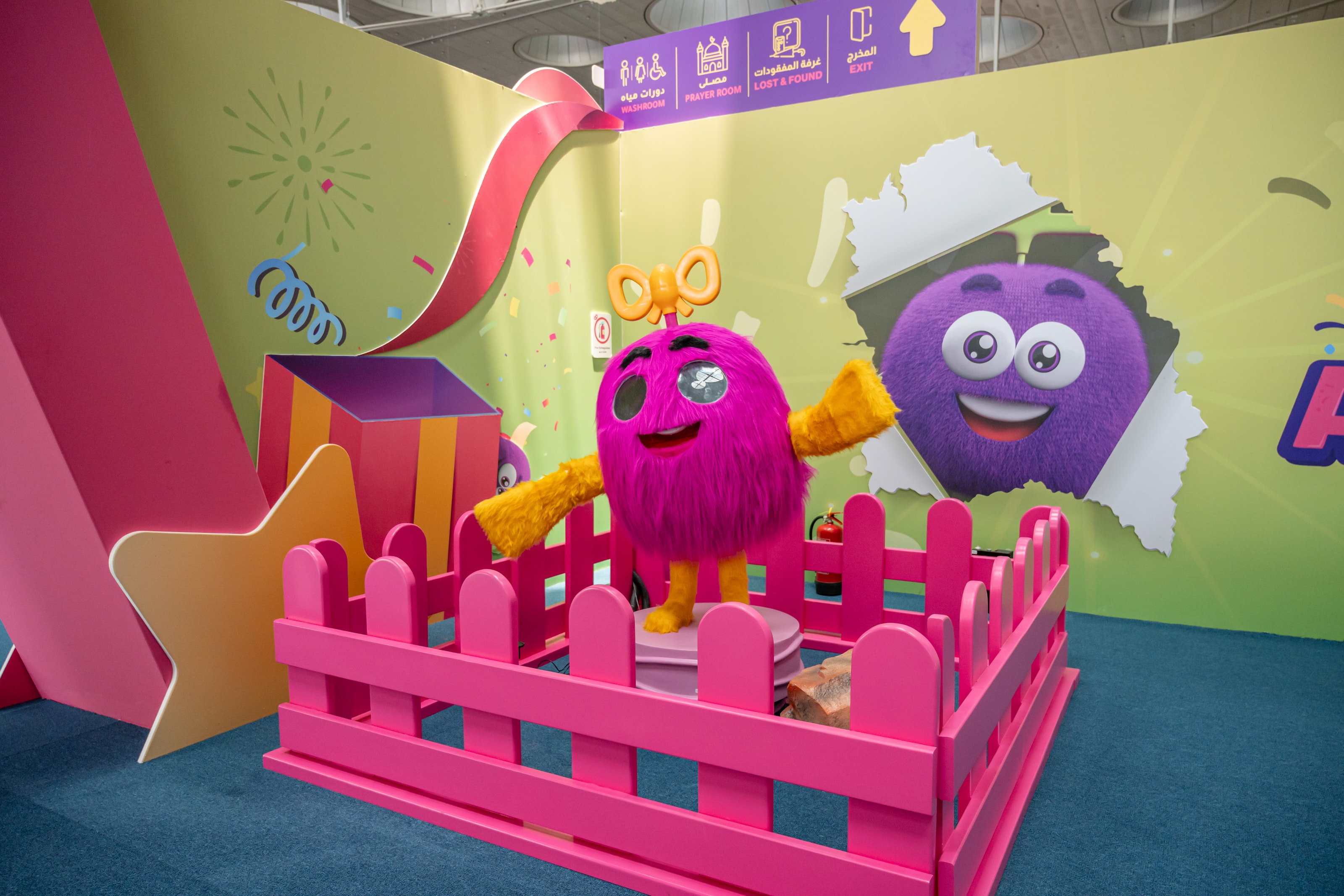 Plush characters in a pink-fenced garden