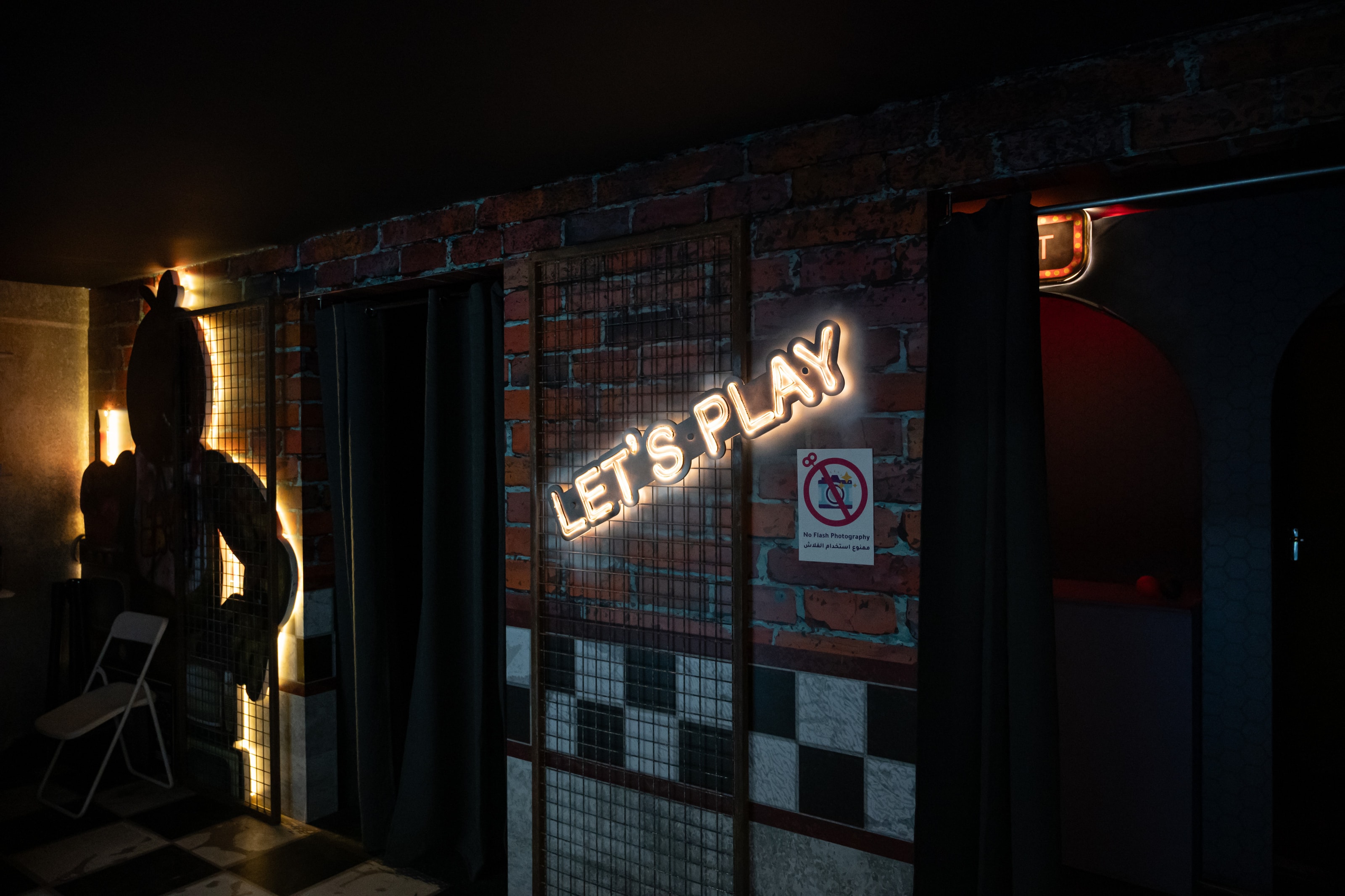 “Let’s play!” neon sign in a dark room