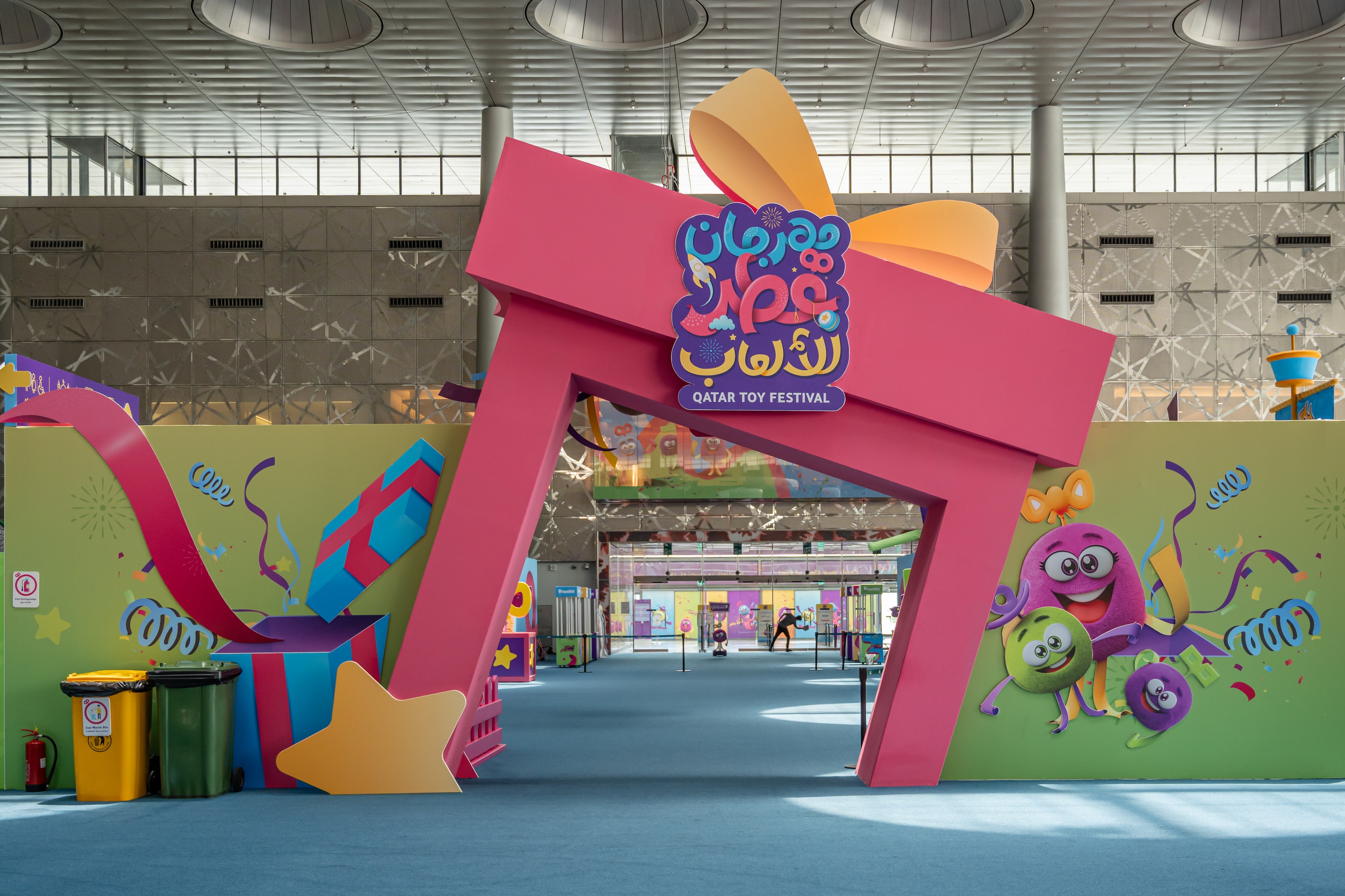 Pink gift-box gate with Qatar Toy Festival lettering in Arabic