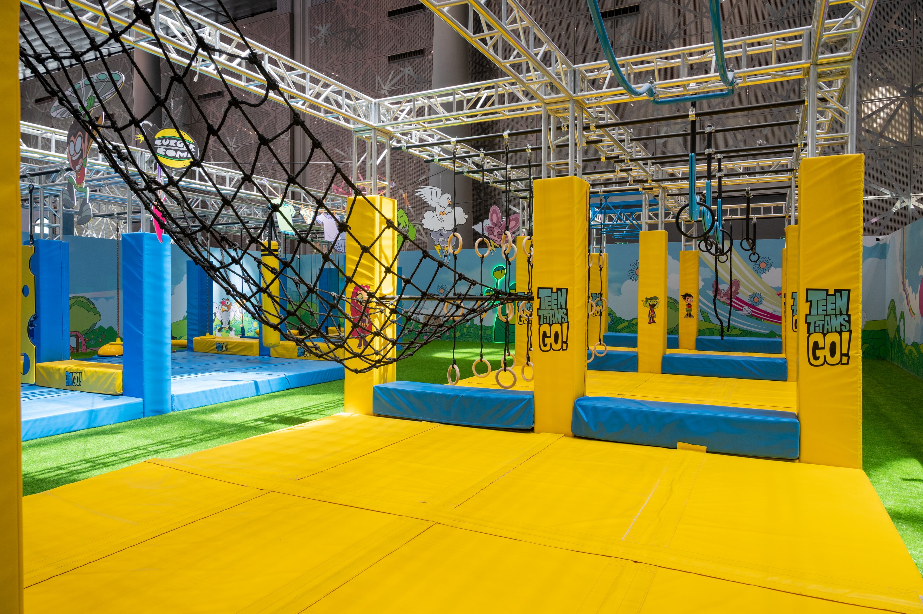 Teen Titans Go! ninja course with yellow and blue padded obstacles under steel rigging