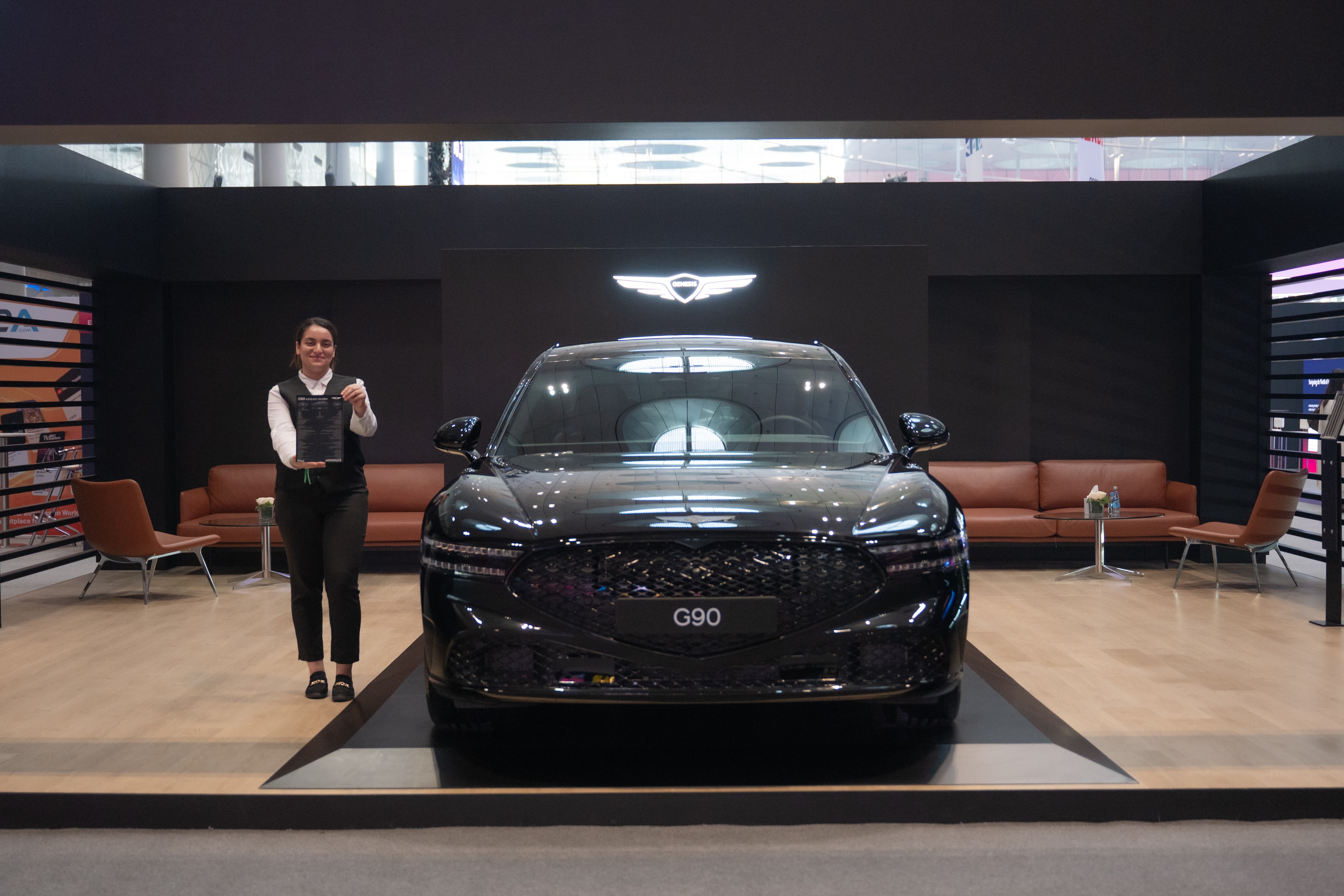 Genesis G90 presented front-on with a host beside it