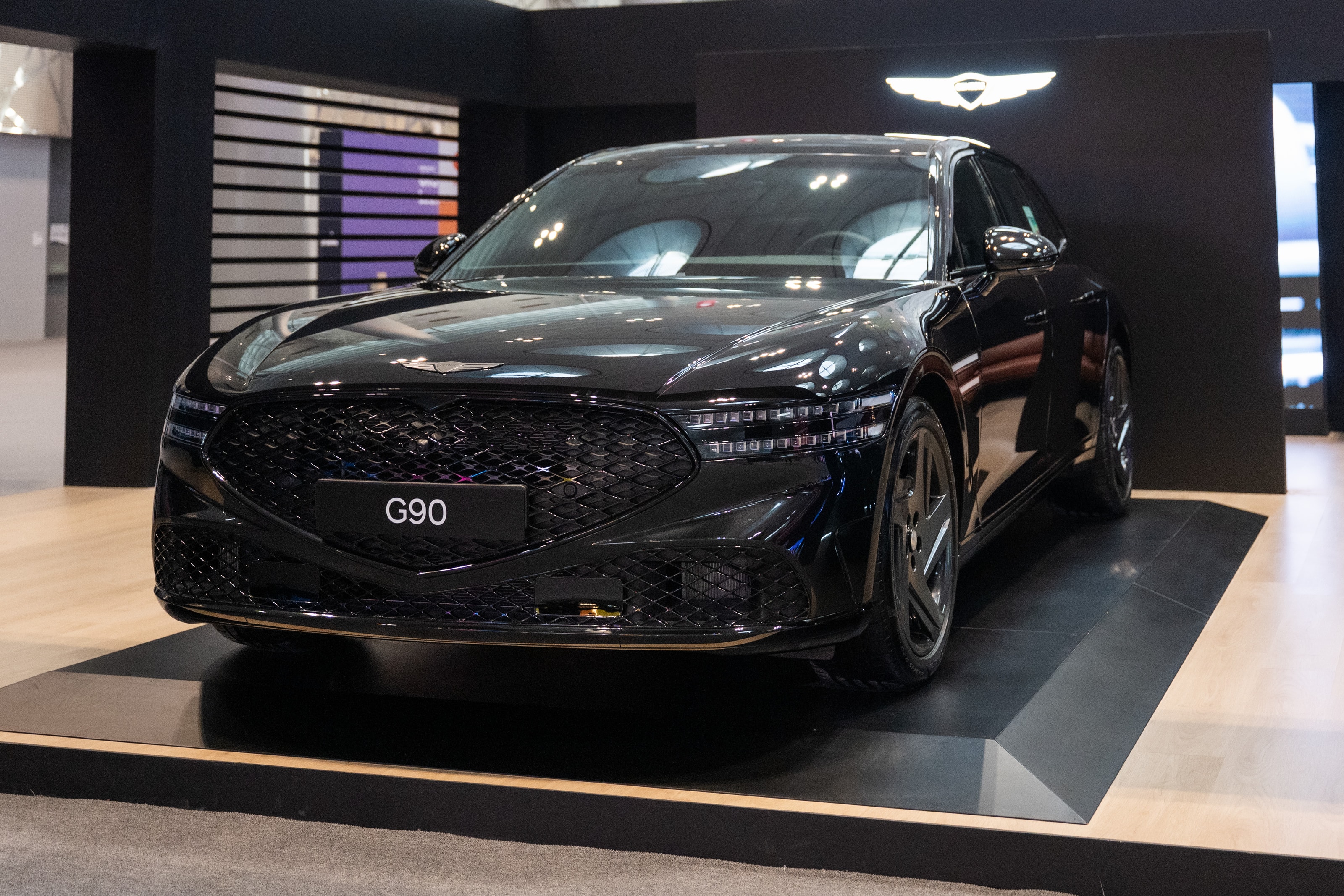 Three-quarter view of the black Genesis G90 on the pavilion