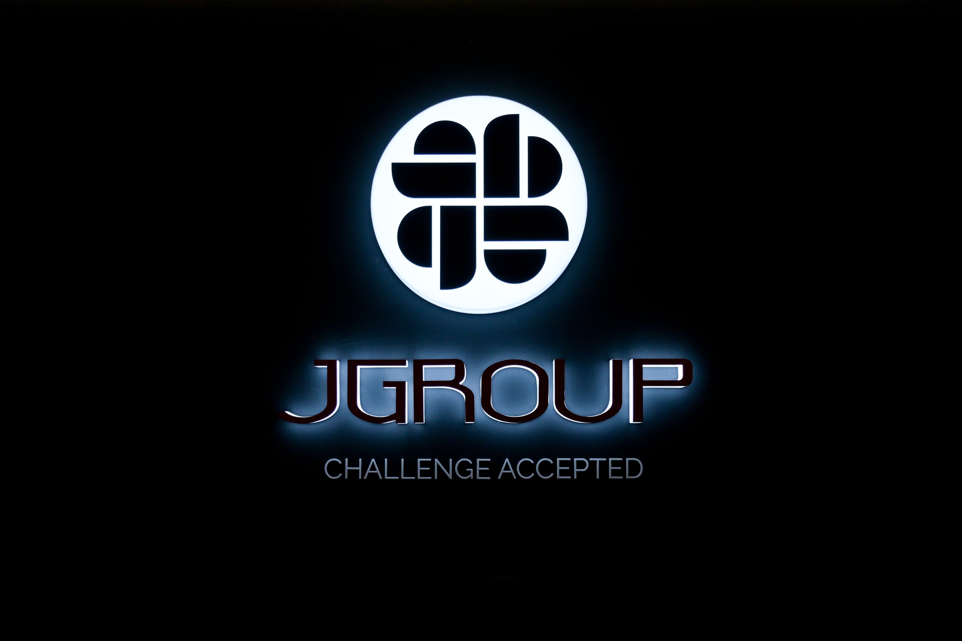 Illuminated J Group logo with the line “Challenge Accepted”
